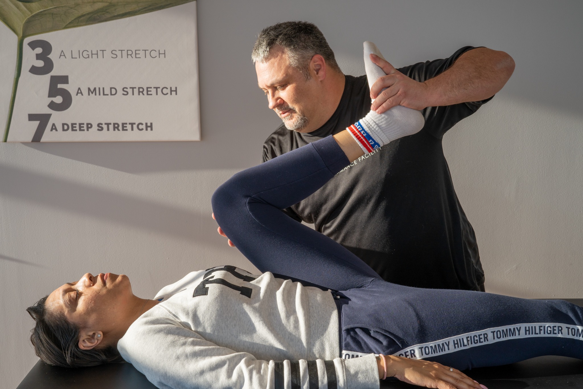 ASA instructor performing an assisted stretch with a client on a professional treatment table